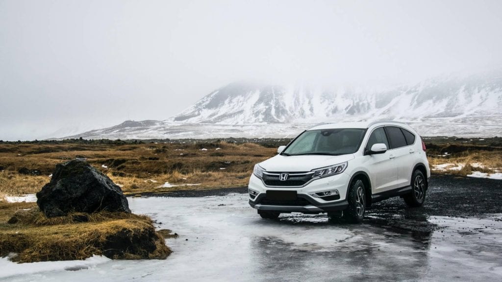 A Honda used car, parked in front of snow-capped mountain backdrop