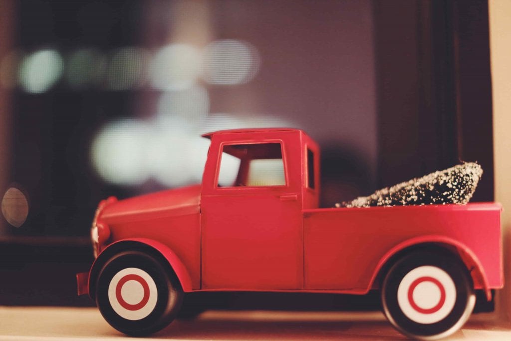 A red plastic pickup truck with a fake Christmas tree in the back.